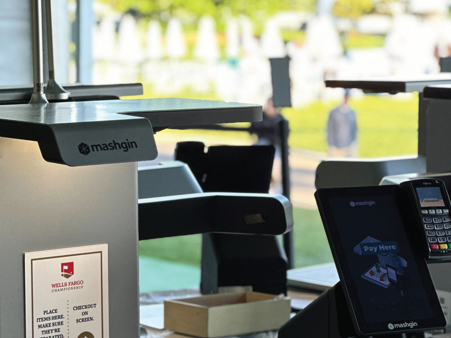 A set of regal Mashgin kiosks with a bright, golf-y backdrop.